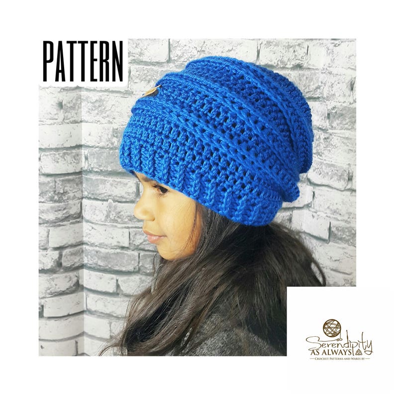 May include: A blue crocheted beanie with a textured stitch pattern. The beanie has a small gold button on the top. The beanie is being worn by a person with long dark hair.