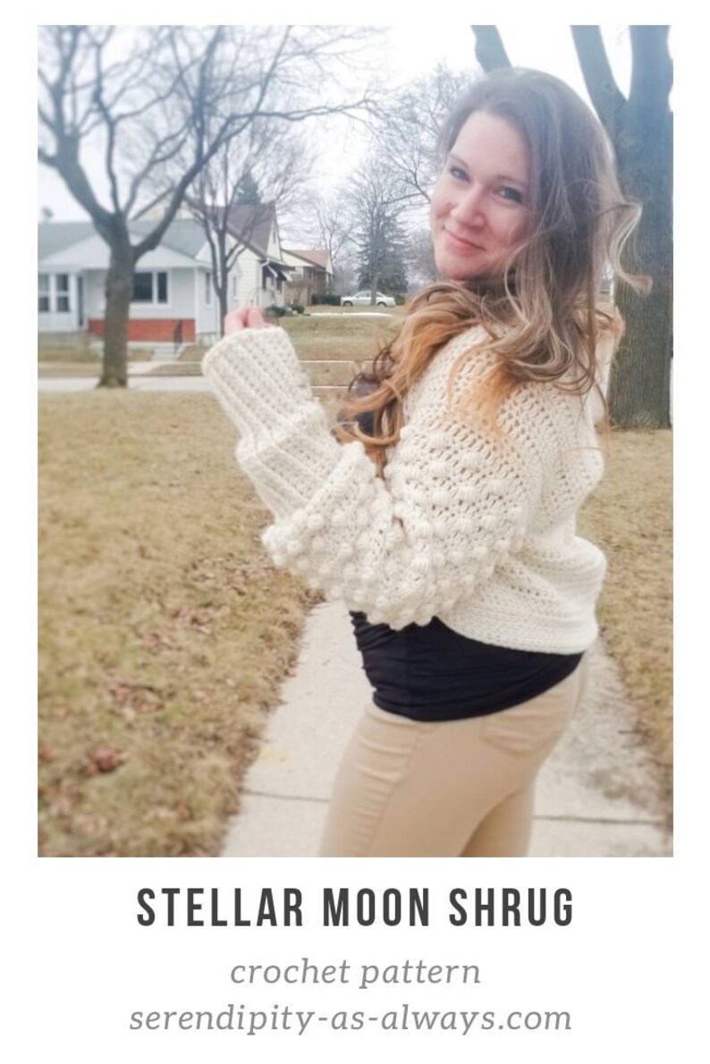 Op de afbeelding: Een witte gehaakte shrug met een textuurpatroon en pofmouwen. De shrug wordt gedragen door een persoon met lang bruin haar. De tekst "STELLAR MOON SHRUN crochet pattern serendipity-as-always.com" is zichtbaar onderaan de afbeelding.