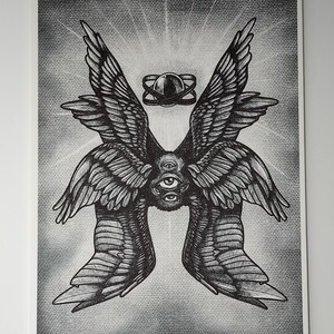 Puede incluir: Un dibujo en blanco y negro de un par de alas con cinco ojos en el centro. Las alas son detalladas y tienen un aspecto texturizado. Un peque&ntilde;o c&iacute;rculo con un anillo alrededor est&aacute; por encima de los ojos.