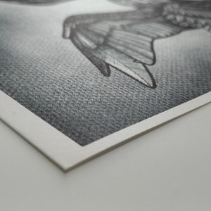 May include: A detailed pencil drawing of a bird in flight, with outstretched wings. The artwork is rendered in grayscale, showcasing intricate feather details and shading. The drawing is on textured paper with a white border.