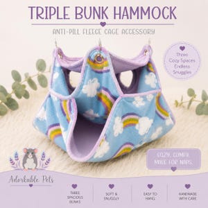 May include: A triple bunk hammock for small pets. The blue fleece cage accessory features a rainbow and cloud pattern. It has three cozy spaces and is easy to hang. The text says "Cozy, comfy, made for naps."