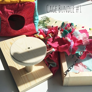Puede incluir: Un conjunto de jaula con una casa de tela rosa y amarilla, una plataforma de madera con una percha redonda, una caja de madera con una cadena y un juguete de forro polar rosa y verde. El texto "CAGE BUNDLE #1" es visible en la imagen.