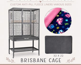 Puede incluir: Una jaula Brisbane de metal gris con soporte y estante, junto a una muestra circular de forro polar azul oscuro con estampado de tiburones y un forro rectangular de forro polar gris oscuro con las dimensiones 32 x 22 cm.