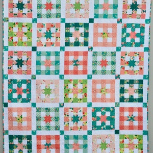 May include: A quilt with a patchwork design featuring a variety of floral and geometric patterns in shades of pink, green, and white.