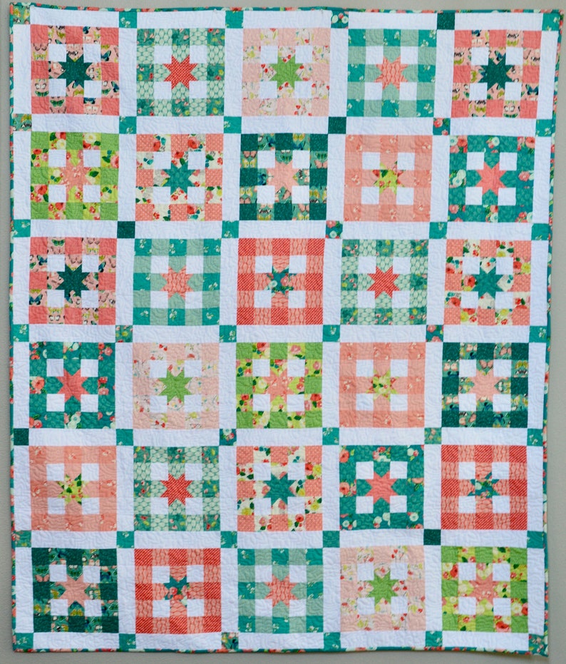 May include: A quilt with a patchwork design featuring a variety of floral and geometric patterns in shades of pink, green, and white.