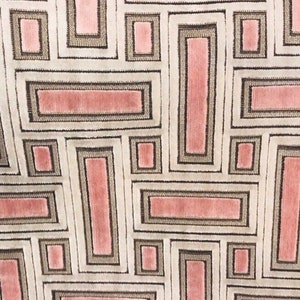 May include: Close-up of a fabric with a geometric pattern. The design features rectangular shapes in shades of pink, gray, and white. The rectangles are outlined with a darker gray, creating a structured, repeating motif. The fabric has a soft, textured appearance.
