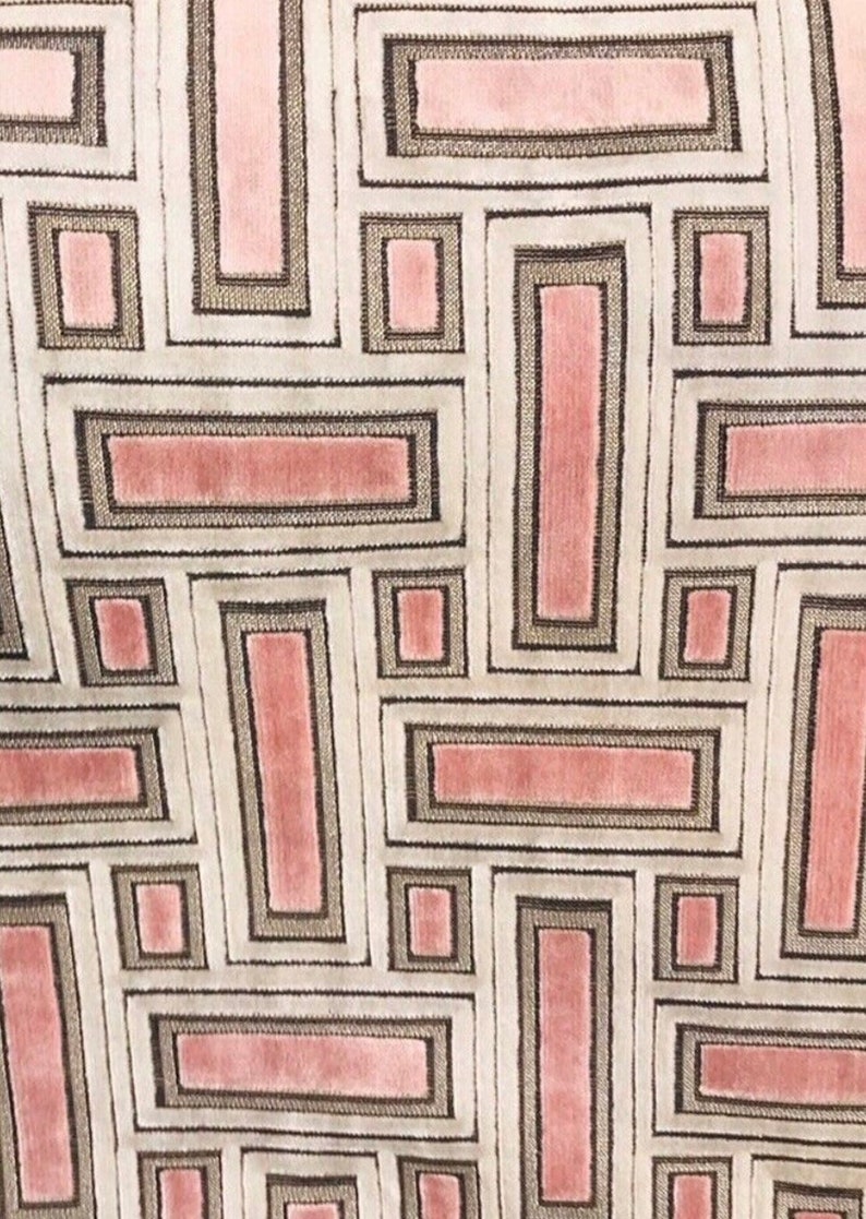 May include: Close-up of a fabric with a geometric pattern. The design features rectangular shapes in shades of pink, gray, and white. The rectangles are outlined with a darker gray, creating a structured, repeating motif. The fabric has a soft, textured appearance.