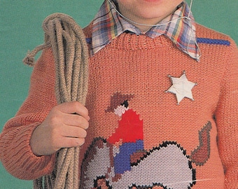 May include: A young boy wearing a cowboy hat and a knitted sweater with a cowboy riding a horse design. The sweater is orange with a white star and a blue and red cowboy. The boy is holding a rope in his right hand.