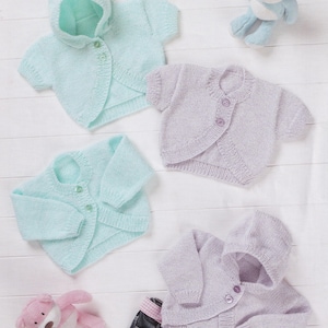 May include: Four pastel-coloured, knitted baby cardigans. Two are light blue, one has a hood. The other two are lavender. Each has button closures. A pink stuffed animal and a blue stuffed animal are in the background. The size range is 35.5-56 cm.