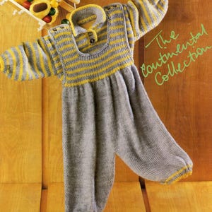 May include: A gray and yellow knitted baby jumpsuit. The top features horizontal yellow stripes and a collar with two buttons. The sleeves and bottom cuffs are trimmed with yellow. The text "The Continental Collection" is visible in the upper right corner.