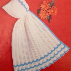 Puede incluir: Manta de bebé de ganchillo blanco con ribete azul y capucha. La manta tiene un borde festoneado.