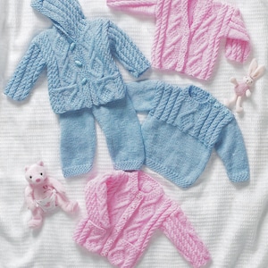 以下が含まれることがあります： 2つのニットのベビーセーターとニットのパンツ1つ。セーターの1つはケーブル編みの模様が入ったピンクで、もう1つはケーブル編みの模様が入ったブルー。パンツはケーブル編みの模様が入ったブルー。セーターとパンツは白い表面に置かれている。