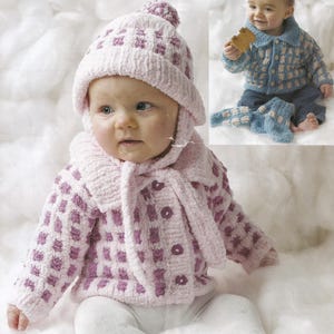 May include: A baby wearing a light pink knitted hat with a pom-pom, a matching jacket, and a scarf. The jacket and hat have a checkered pattern in a darker shade of pink. The baby is sitting on a white, fluffy surface.