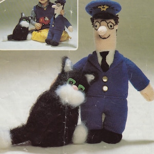 May include: Knitted Postman Pat doll in a blue uniform, with a black tie, and a matching hat. A black and white knitted cat with green eyes sits next to the doll. The image is a close-up of the doll and cat.