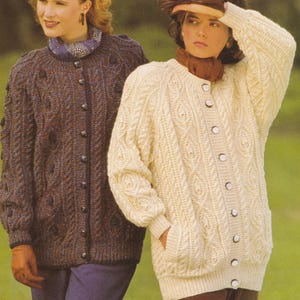 May include: Two women modelling Aran knit cardigans. One is dark brown, the other cream. Both have button fastenings and detailed cable knit patterns. The image is set outdoors, with the word 'ARAN' visible in the top left corner.