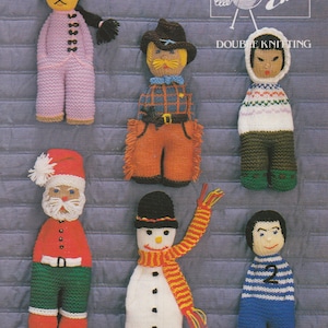 May include: A collection of knitted dolls, each with unique outfits and features. The dolls include a Santa Claus, a snowman with a striped scarf, a cowboy, a soccer player, and others. The image also includes the text "Emu Double Knitting".