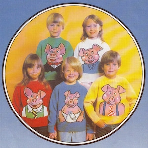 May include: Five children wearing colorful sweaters with pig designs. The sweaters are all different colors and have different pig designs. The children are smiling and looking at the camera.