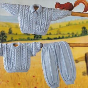 May include: A light blue knitted baby outfit, comprising a collared cardigan, a short-sleeved sweater, and bloomers. The clothes are displayed on a wooden rod, with a painted backdrop of a field and a squirrel.