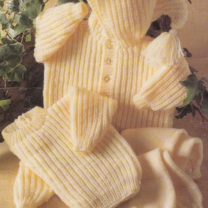 May include: A set of knitted baby clothes in a pale yellow colour. The set includes a hooded sweater, a pair of trousers, and a matching hat.