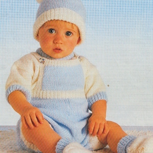 May include: A baby wearing a blue and white knitted hat, a blue and white striped knitted onesie, and white knitted booties.