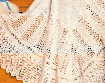 May include: A white crocheted baby blanket with a delicate lace pattern. The blanket measures 48 inches or 122 cm.