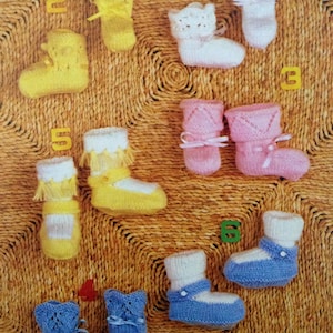 May include: A set of ten knitted baby booties in various colors and styles, including white, pink, yellow, and blue. The booties are displayed on a woven surface.
