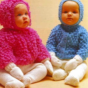 May include: Two babies wearing knitted outfits. One baby is wearing a pink sweater and hat with white mittens. The other baby is wearing a blue sweater and hat with white mittens.