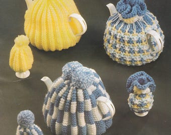 May include: A set of five knitted teapot and tea cosy covers. The covers are in blue and white stripes, yellow, and blue and white with a chequered pattern. The covers are all topped with pom-poms.