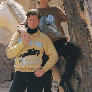 May include: Two knitted jumpers with equestrian designs. One is yellow with a black horse and rider, and blue accents. The other is brown with a large horse head design in grey and blue. Both jumpers have long sleeves.
