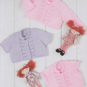 May include: Three knitted baby cardigans in pink and lavender with button closures. The cardigans have a delicate lace pattern and short sleeves.