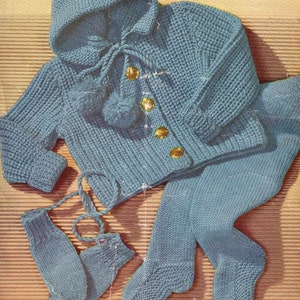 May include: A blue knitted baby outfit with a hooded jacket, pants, and booties. The jacket has a tie at the neck and buttons down the front. The outfit is made with a textured knit stitch.