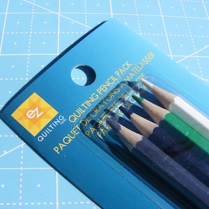 May include: A package of quilting pencils in a blue plastic sleeve. The pencils are in shades of green, white, and blue. The package has the text "Quilting Pencil Pack" and the "ez quilting" logo.