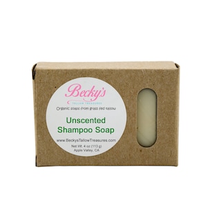 Puede incluir: Una caja de cartón marrón con una etiqueta circular que dice "Becky's Unscented Shampoo Soap". La caja tiene una ventana rectangular que muestra una pastilla de jabón. La etiqueta también incluye el sitio web y el peso neto de 113 g.