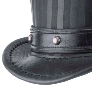 May include: A black leather top hat with a striped fabric crown and a leather band with silver studs.