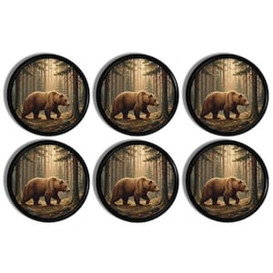 May include: A set of six circular coasters, each featuring a brown bear walking through a dense, misty forest with tall pine trees. The coasters have a thin black border framing the detailed illustration of the bear in its natural habitat.