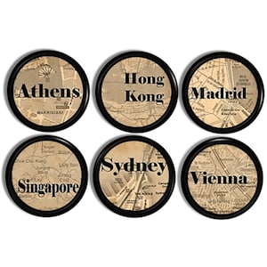 Peut inclure: Un ensemble de six dessous de verre circulaires à bordure noire, chacun présentant un fond de carte vintage aux tons sépia. Les dessous de verre portent les noms de ville Athens, Hong Kong, Madrid, Singapore, Sydney et Vienna en gras.