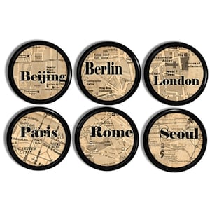 May include: A set of six circular coasters with black frames, each featuring a vintage-style map background in beige and brown tones. The coasters are labeled with the city names Beijing, Berlin, London, Paris, Rome, and Seoul in bold black text.