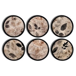 May include: A set of six circular coasters, each featuring a black frame and a beige background decorated with a detailed botanical print of various dark brown and black leaves, twigs, and foliage arranged in a natural, layered composition.