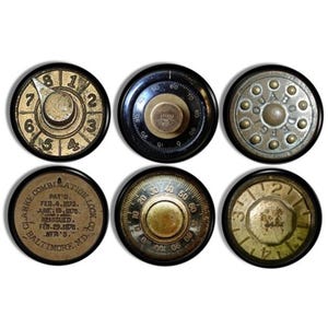 May include: Six vintage combination lock dials with black rims and brass colored numbers and markings. The dials have different designs and numbers. One dial has the text "CLARKE COMBINATION LOCK CO. PAT'D FEB. 4. 1873. JUNE. 15. 1876. REISSUED. FEB. 29. 1976. MFR'S. BALTIMORE. MD."