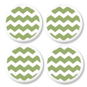 May include: Four circular coasters with a white edge. Each coaster displays a green and white chevron design. The coasters are arranged in a square formation against a white backdrop.