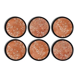 May include: Set of six round coasters. Each coaster features a terracotta-colored background with a white leaf pattern. The coasters have a black border.