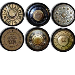 Puede incluir: Seis diales de cerradura de combinaci&oacute;n de aspecto antiguo con bordes negros. Los diales tienen diferentes dise&ntilde;os y n&uacute;meros. Un dial tiene el texto "CLARKE COMBINATION LOCK CO. BALTIMORE, MD. MFR'S. PAT'D. FEB. 4, 1973. JUNE 15, 1975. REISSUED. FEB. 29, 1976."