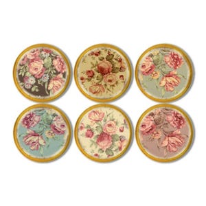 May include: Six round coasters with floral designs. Each coaster features a different arrangement of pink, red, and yellow roses with green leaves on a variety of backgrounds, including brown, cream, and blue. The coasters have gold-colored edges.