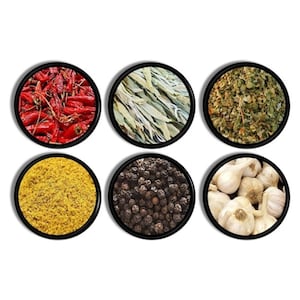 May include: Six circular containers with black rims, each filled with different spices. The spices include red chili peppers, dried sage leaves, dried herbs, yellow powder, black peppercorns, and whole garlic bulbs. The containers are arranged in two rows of three.
