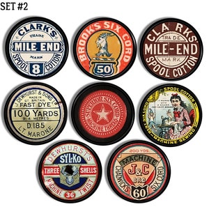 Op de afbeelding: Een verzameling vintage spoel katoenen labels met verschillende ontwerpen en tekst. De labels zijn rond en hebben een zwarte rand. Sommige van de labels bevatten de tekst "Clark's Trade Mile-End Mark", "Brooks Six Cord", "Superior Six Cord Machine Thread", "Dewhurst & Sons Made in Gt. Britain Fast Dye 100 Yards 91/4 Metres D.185 Lt. Marone", "Dewhurst's Sylko Three Shells Machine 36 Twist", en "Chadwick's 200 Yds. Machine J&C Bro 60 Six Cord".