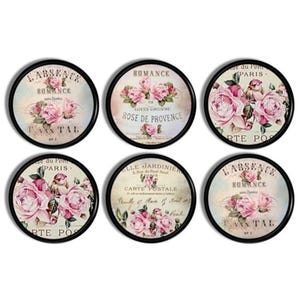 Peut inclure: Six dessous de verre ronds avec des bordures noires, présentant des motifs floraux vintage. Chaque dessous de verre affiche des roses roses et du texte français, dont "Romance" et "Rose de Provence."