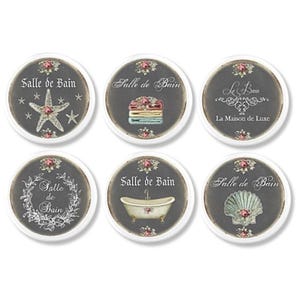 May include: Six round bathroom signs with a dark grey background and white trim. Each sign features a different design, including a starfish, towels, a seashell, and the text "Salle de Bain".