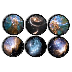May include: Six circular coasters with black borders, each displaying a different image of a nebula or galaxy. The images show vibrant blues, oranges, and yellows, with swirling patterns and stars, creating a cosmic theme.