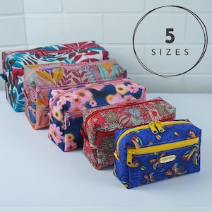 May include: Five rectangular zippered pouches in varying sizes and colorful floral or butterfly patterns. Each pouch features a top zipper closure, and the smallest blue pouch has a front zippered pocket with a gold-toned brand label reading anjurina.