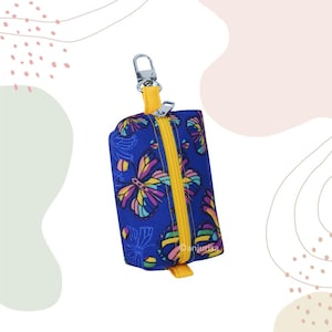 May include: A small, rectangular blue pouch with a yellow zipper and a silver clasp. The pouch is decorated with colorful butterfly patterns. The zipper and the strap are yellow. The pouch is designed to be attached to a keychain.